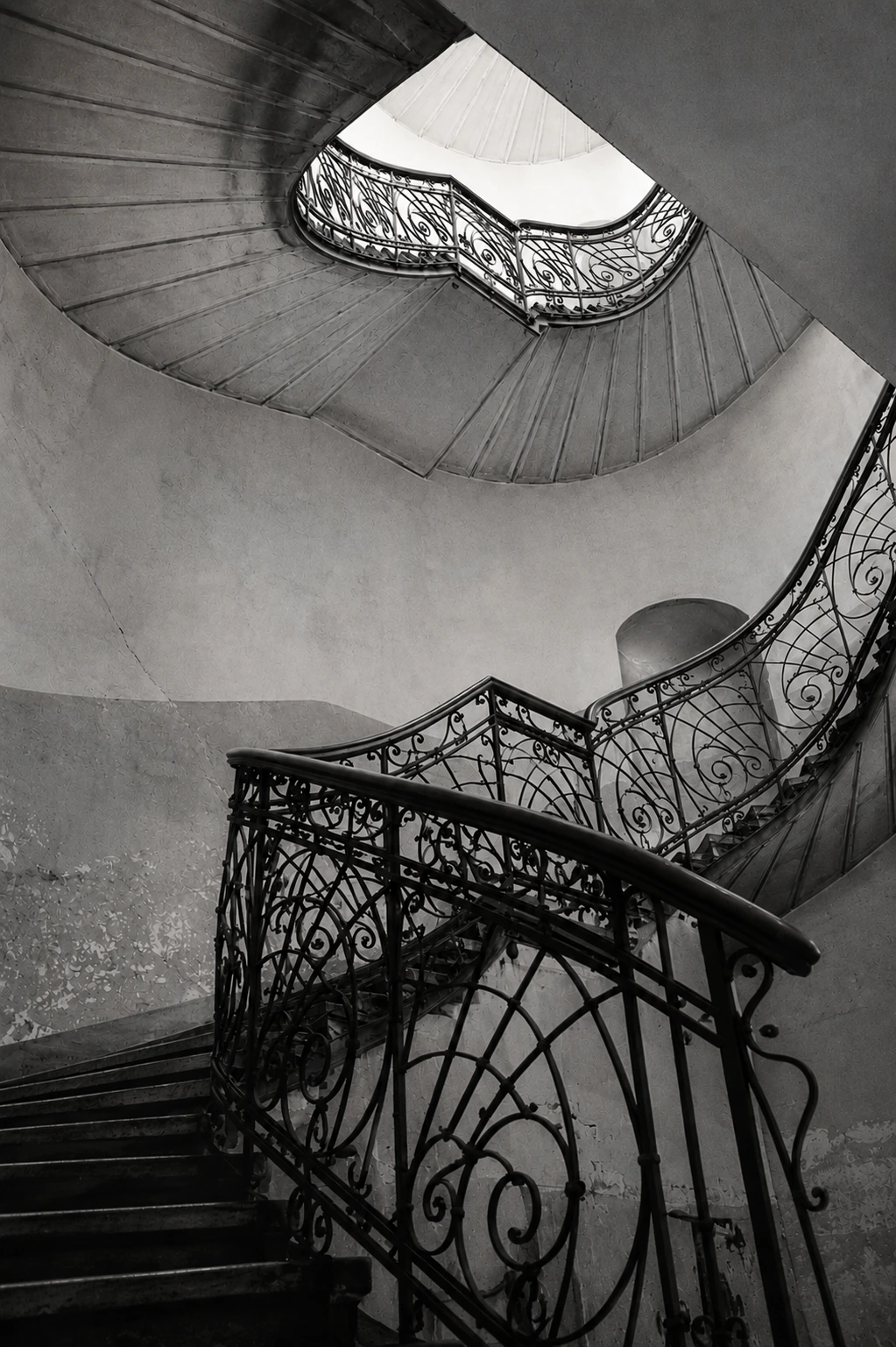 Black and white fine art photograph of a spiral staircase, emphasising sweeping architectural lines and geometric symmetry.